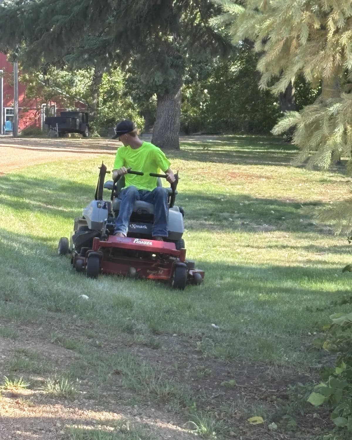 Lofton crew member mowing a shaded lawn on a zero-turn mower — photo taken by the customer