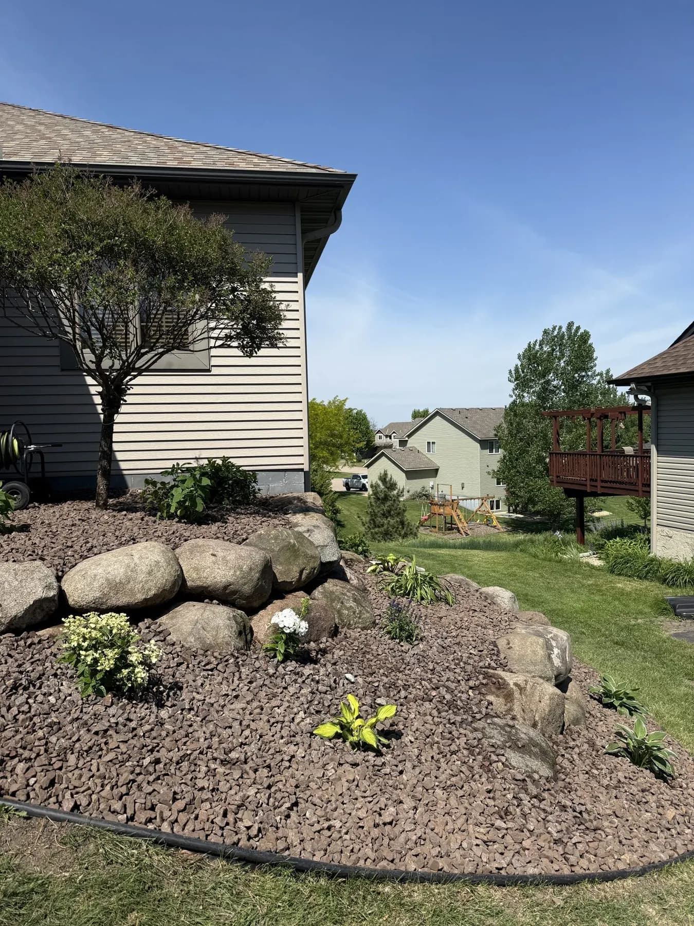 Boulder retaining edge and planted bed on a sloped back yard in Savage, Minnesota