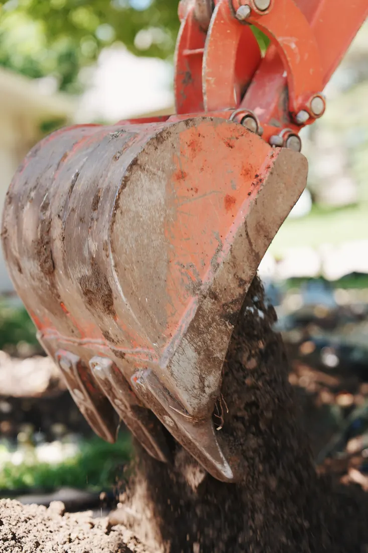 Excavator bucket pouring soil during a bed rebuild