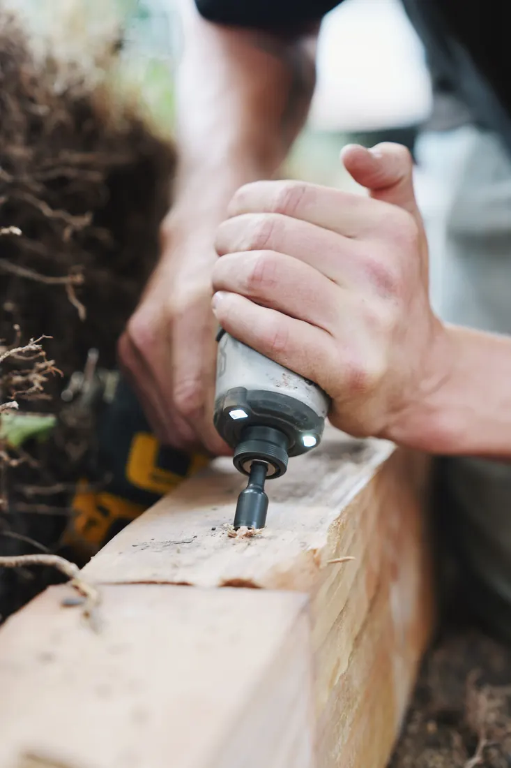 Close-up of an impact driver sinking a spike into a timber