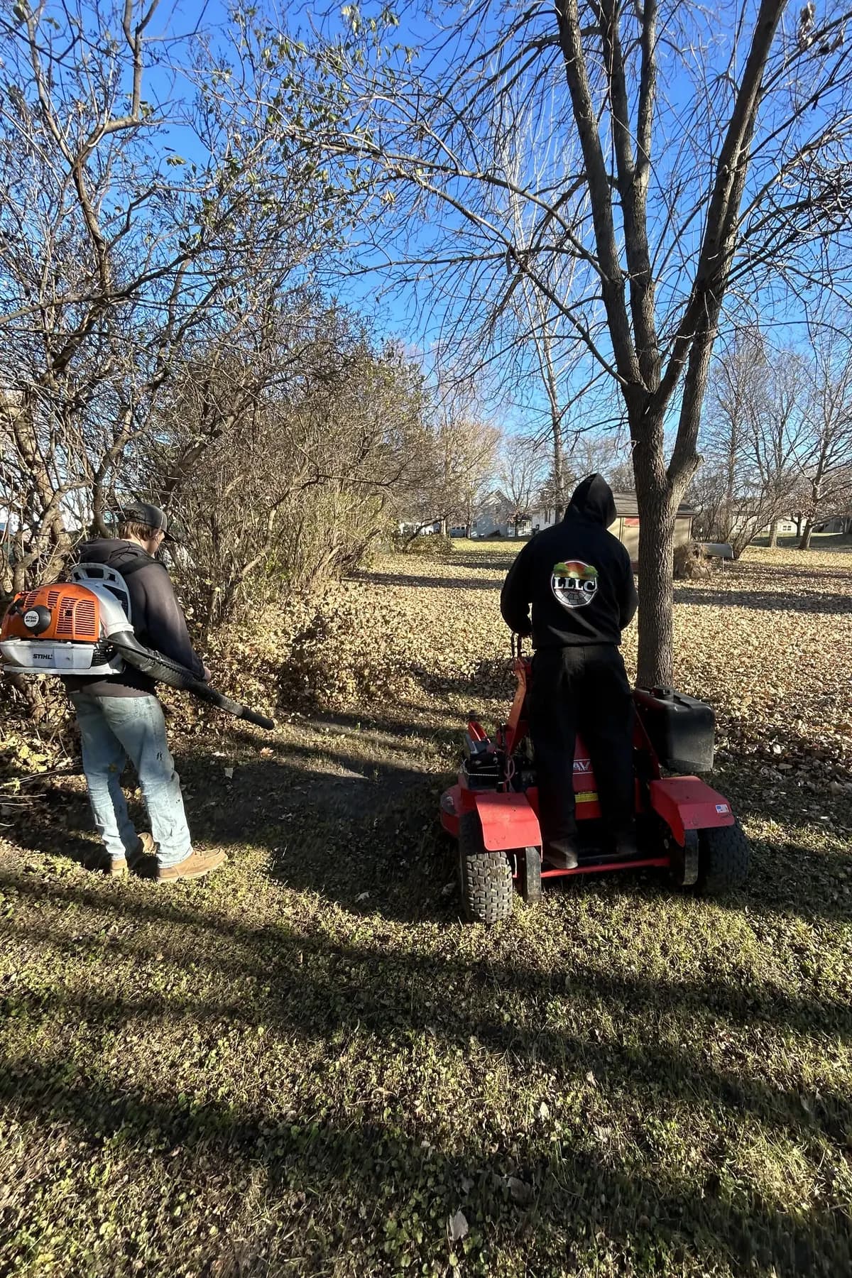 Lofton crew clearing fall leaves with a stand-on blower and backpack blower